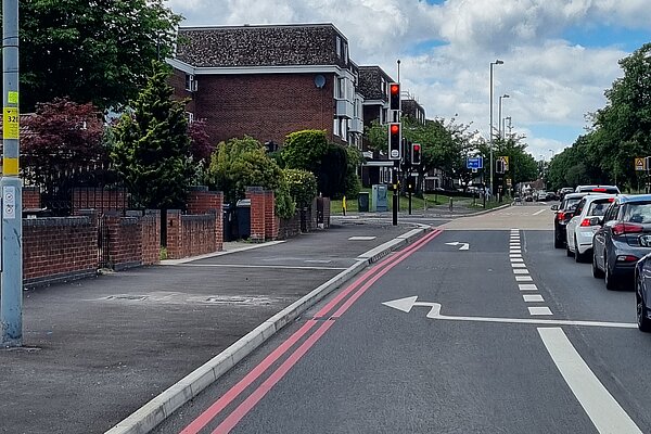 Road with heavy traffic next to pavement missing a bus stop